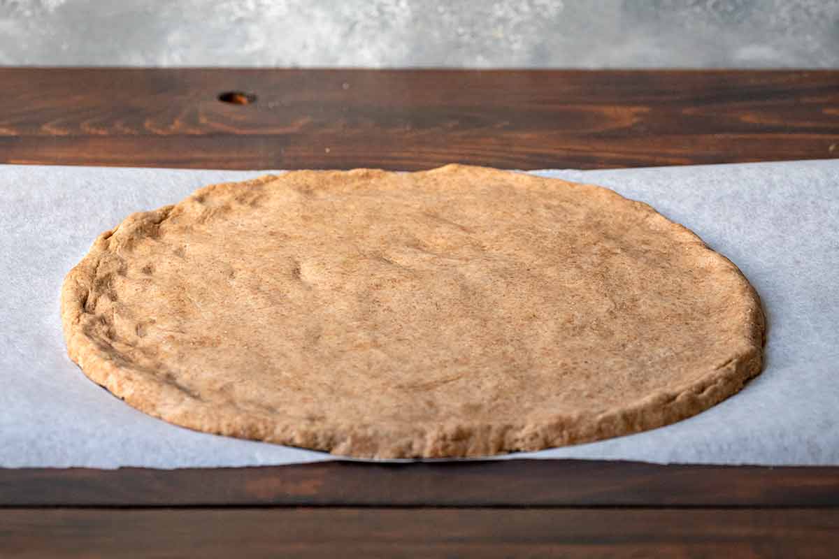 Pizza dough on a piece of parchment paper.